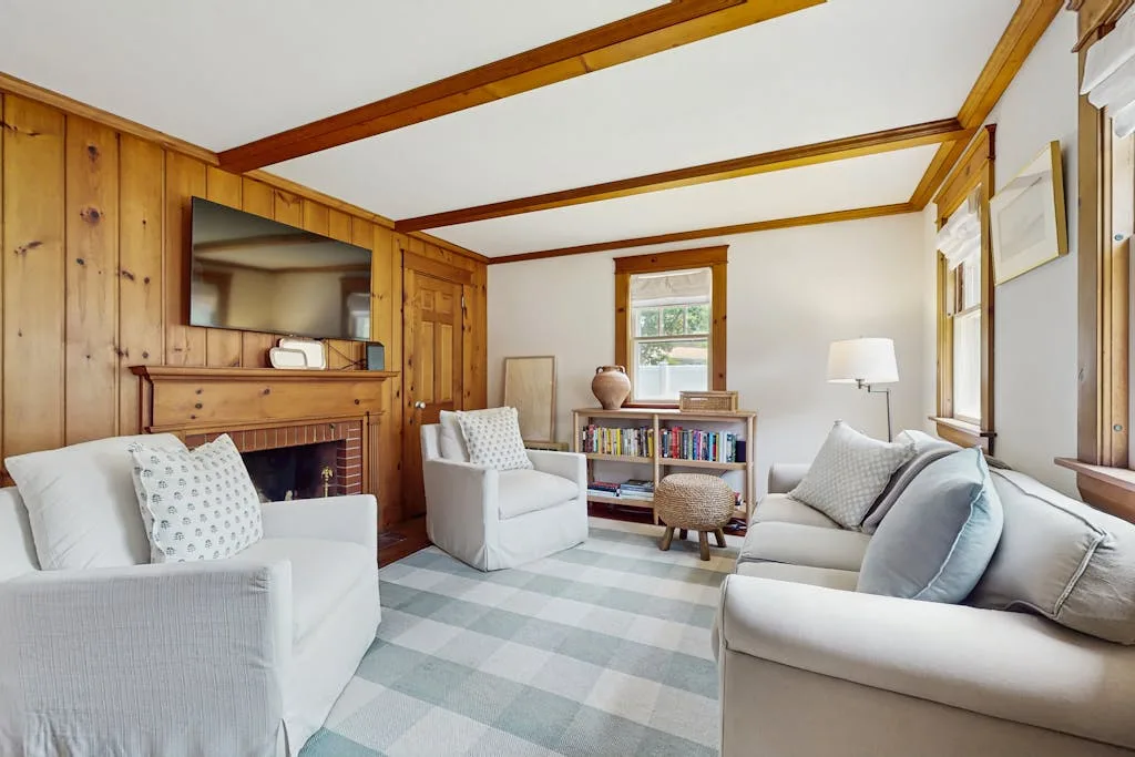 A wood-paneled living room with seating, a fireplace, and a small bookcase.