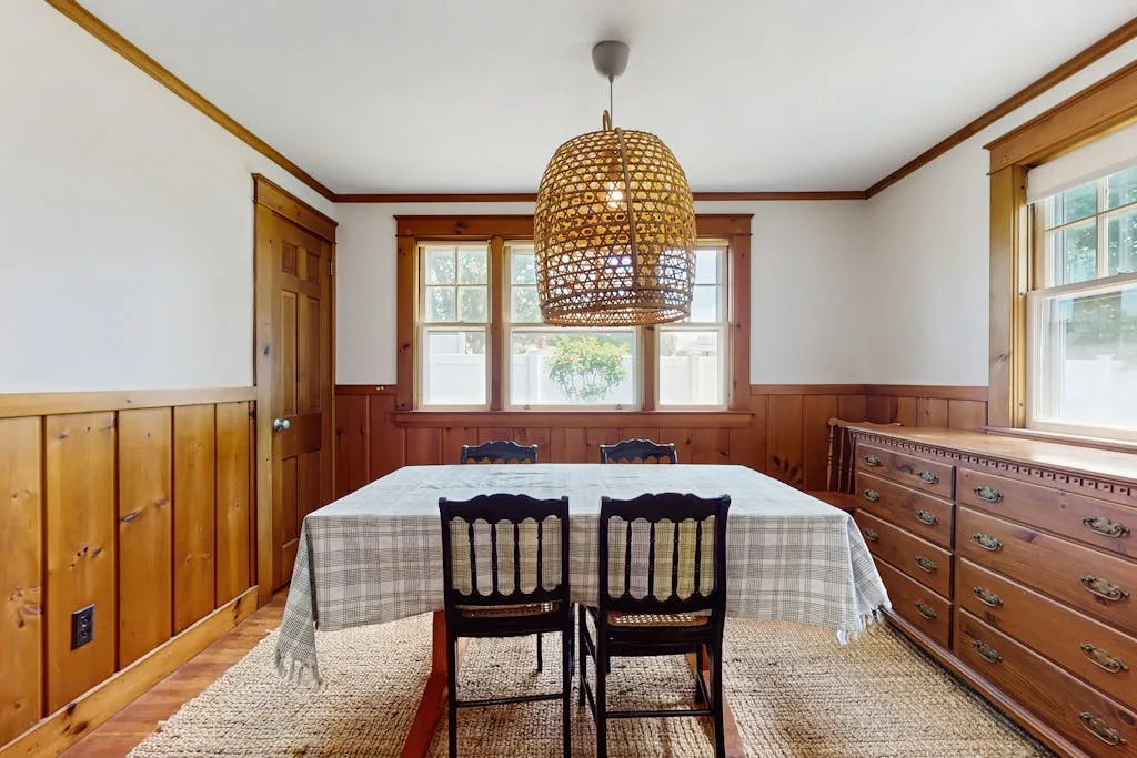 A dining room with a large table beneath a woven pendant light.