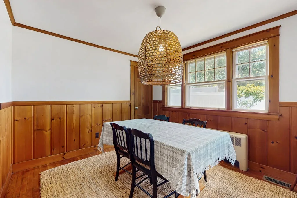 A dining room with a table and chairs beside large windows.