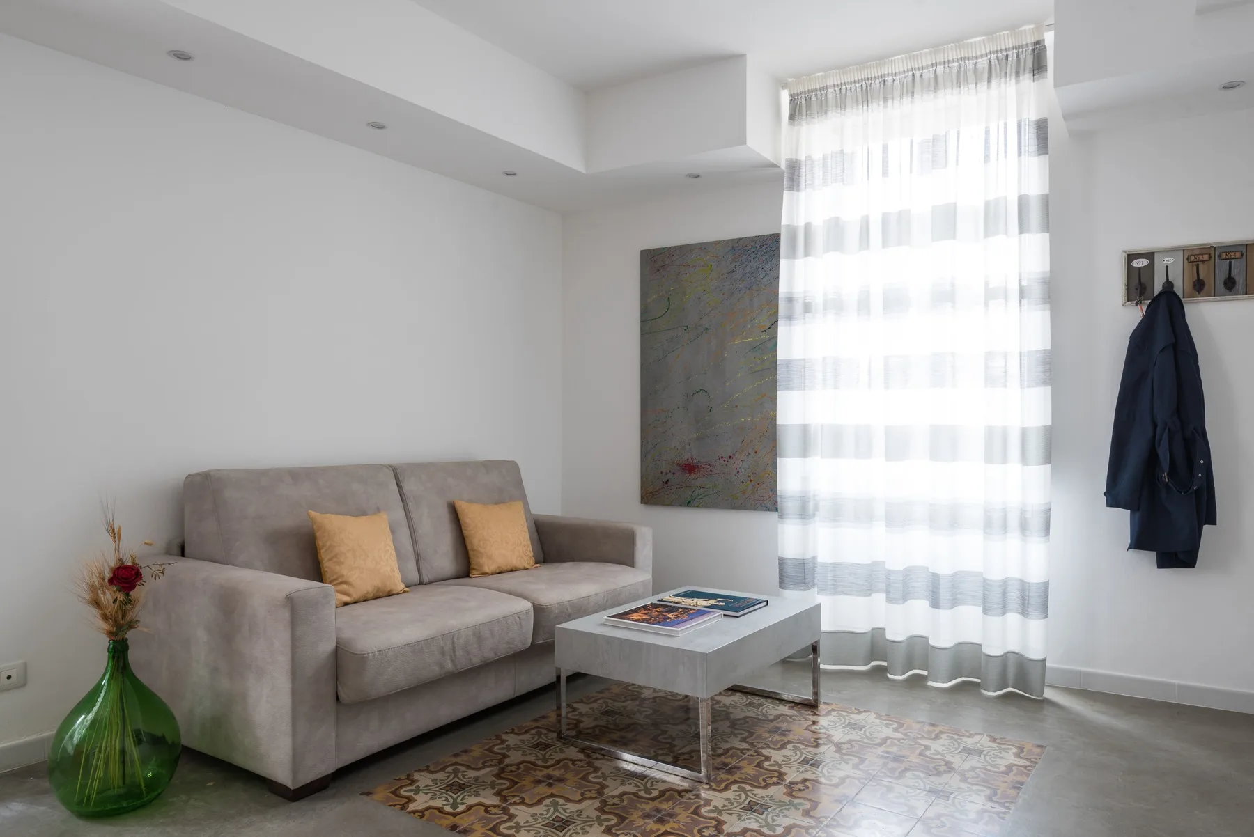 A living room with a sofa, coffee table, and sheer curtains.