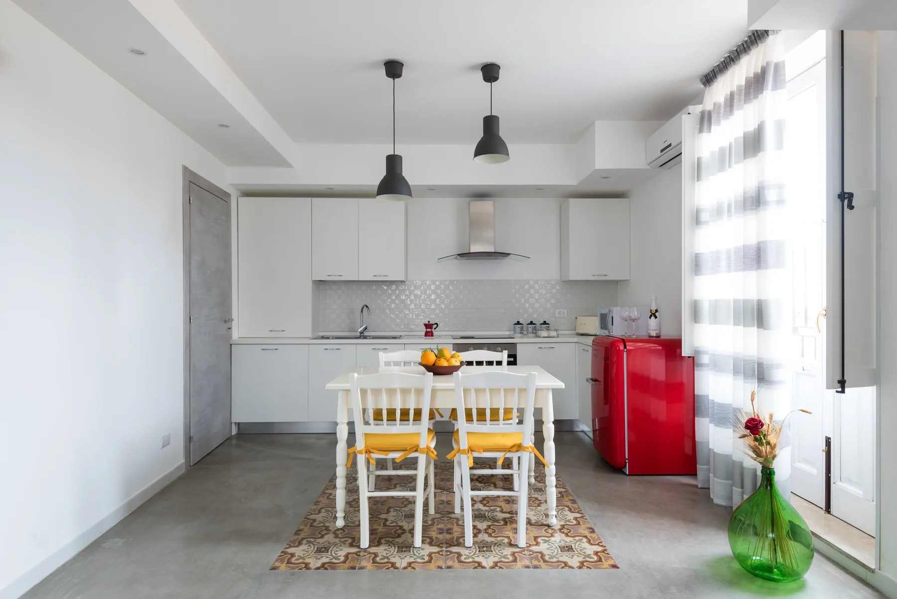 A bright kitchen and dining area with white cabinets, a table, and chairs.