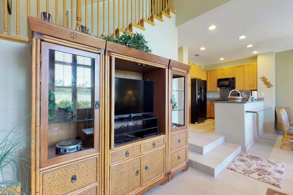 An open-plan living and kitchen area features a television cabinet and a kitchen island.