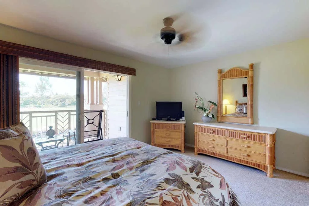 A bedroom with a bed, dresser, and sliding glass doors opening to a balcony.