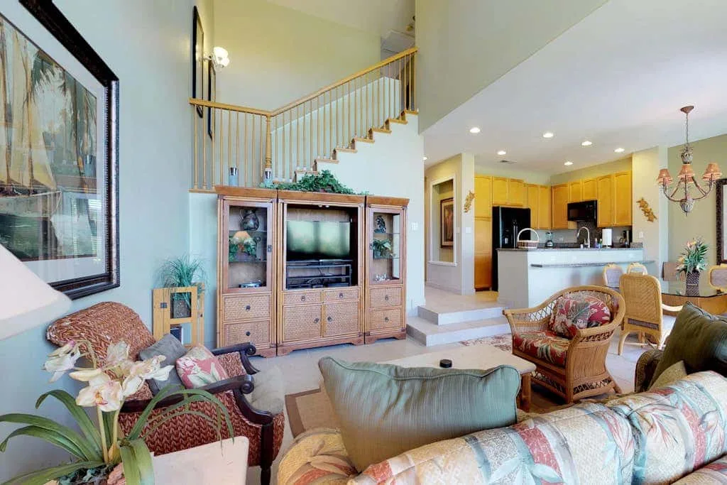 A living room opens onto a staircase and a kitchen with a breakfast bar.