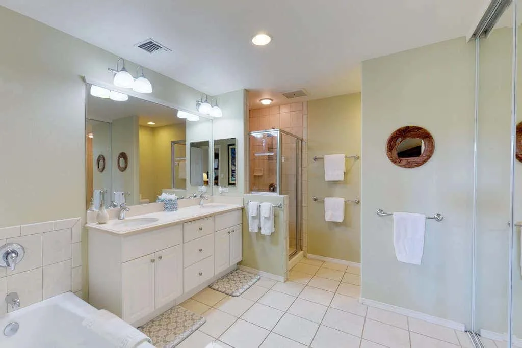 A bright bathroom with a long vanity, large mirror, and glass shower.