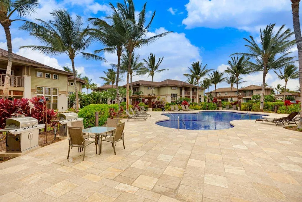 An outdoor pool area with patio seating and palm trees.