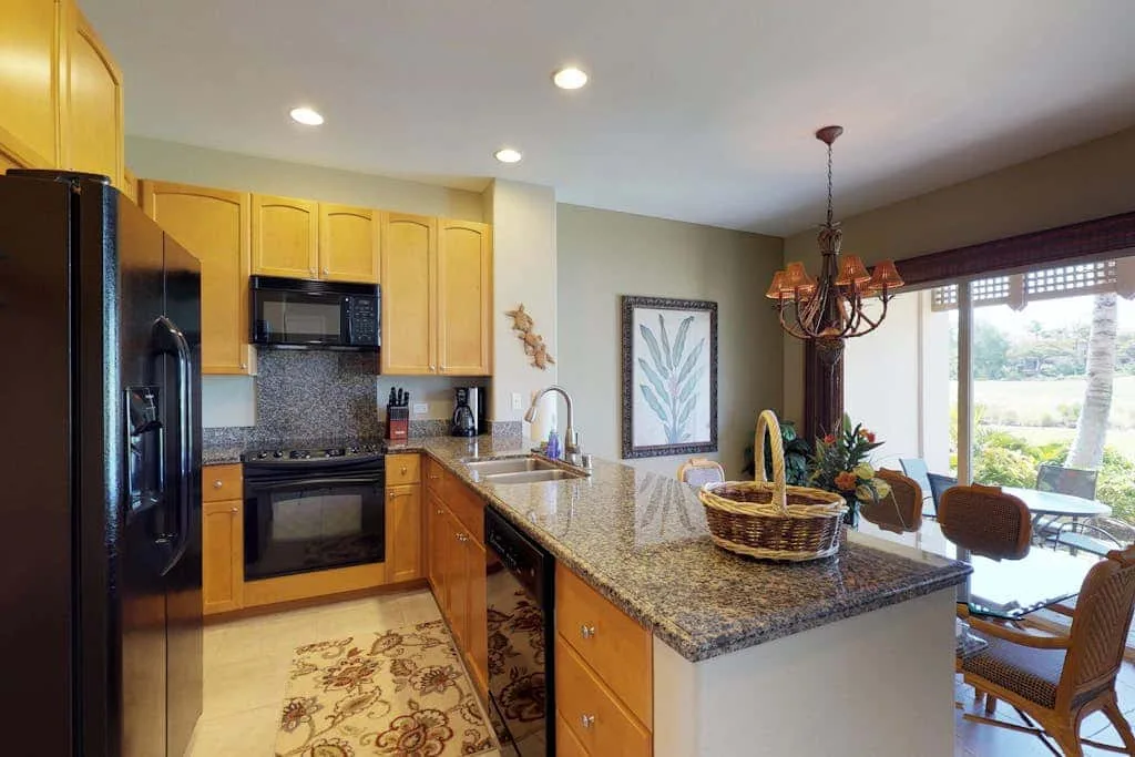 A kitchen with wooden cabinets and a countertop island opens onto a dining area.
