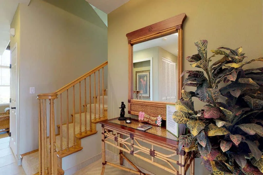 An entryway with a wooden staircase, a console table, and a large mirror.