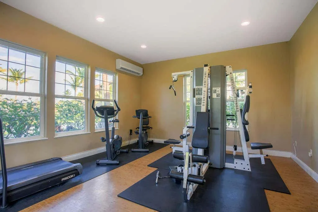 A small gym with exercise machines and large windows.