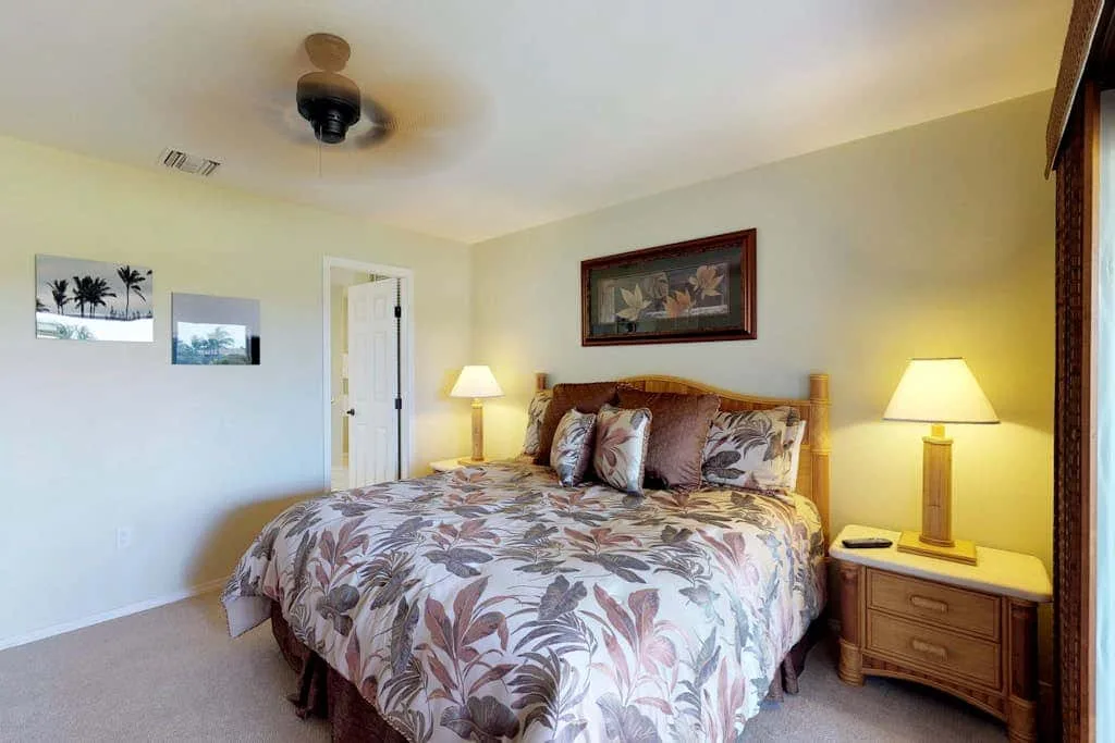 A bedroom with a floral-patterned bedspread and bedside lamps.