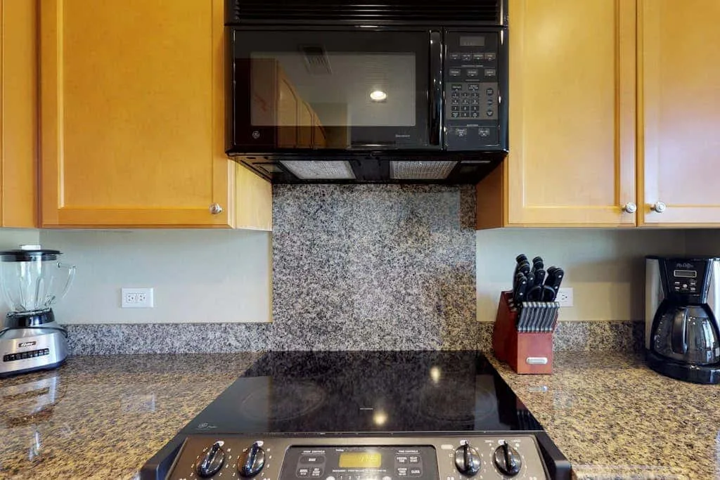 A kitchen counter with a cooktop, microwave, and small appliances.