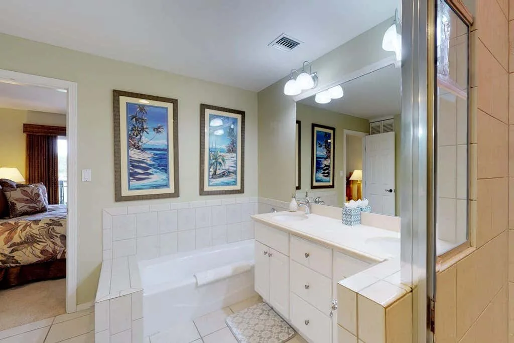 A bathroom with a bathtub, vanity, and large mirror.
