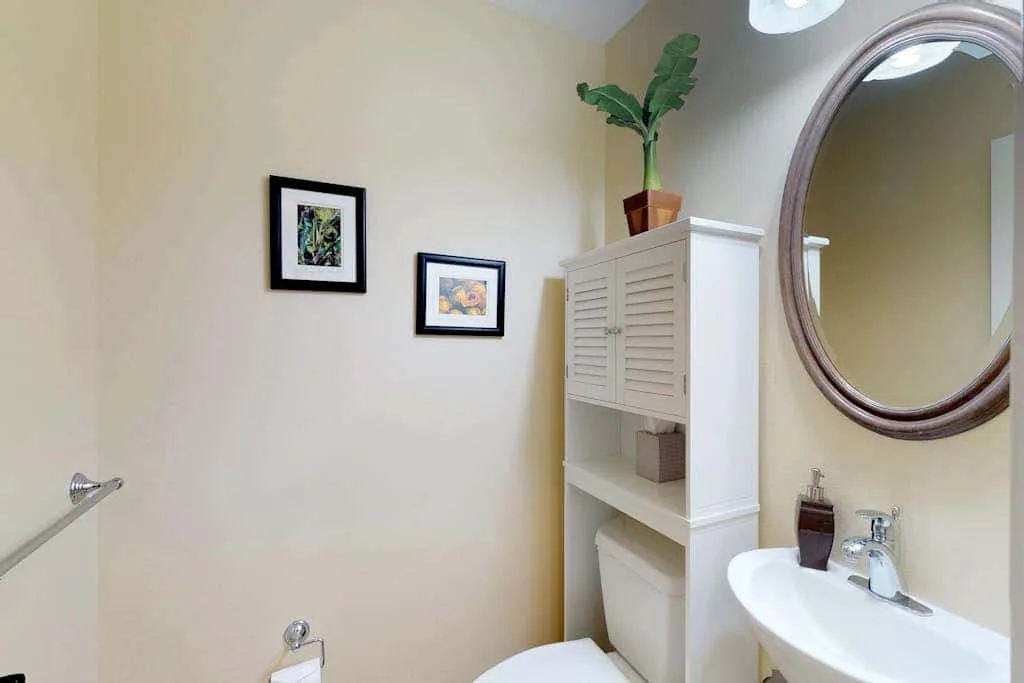 A bathroom with a sink, toilet, and wall-mounted framed pictures.