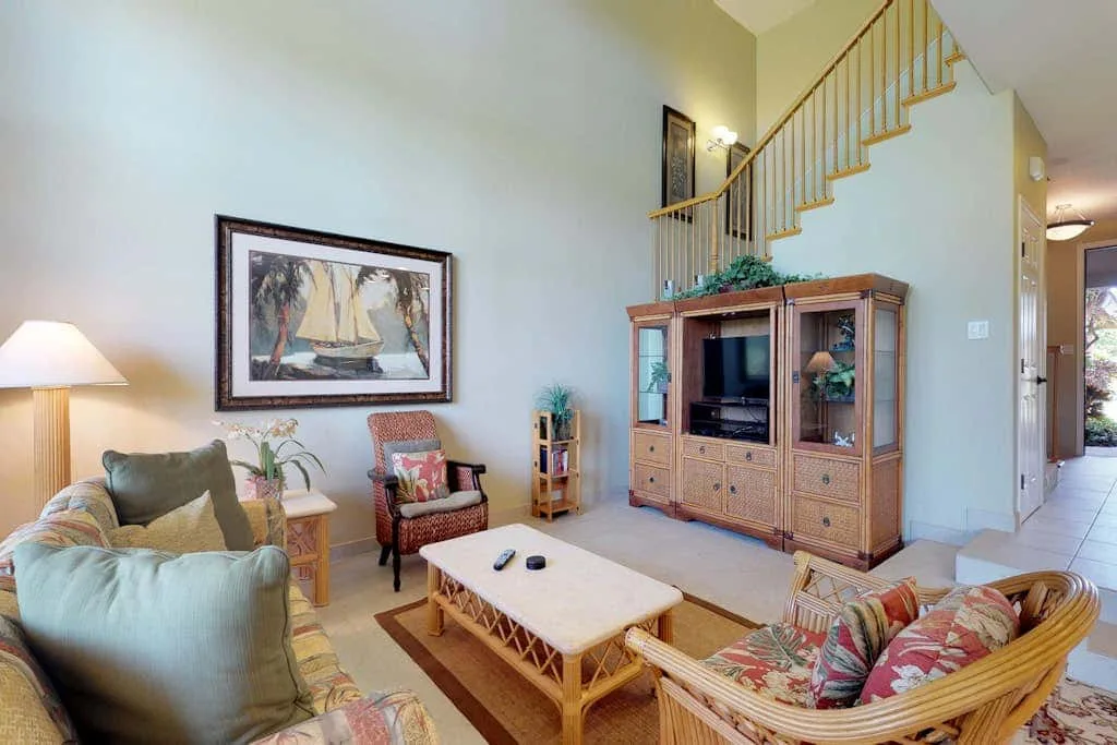 A living room with a television cabinet, seating, and a staircase.