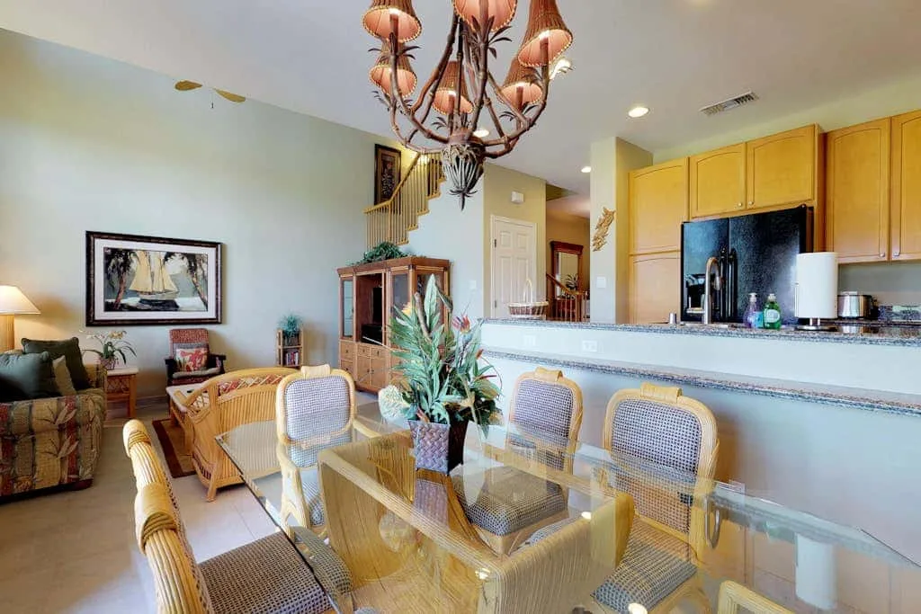 A dining area with a glass table and an open kitchen behind it.