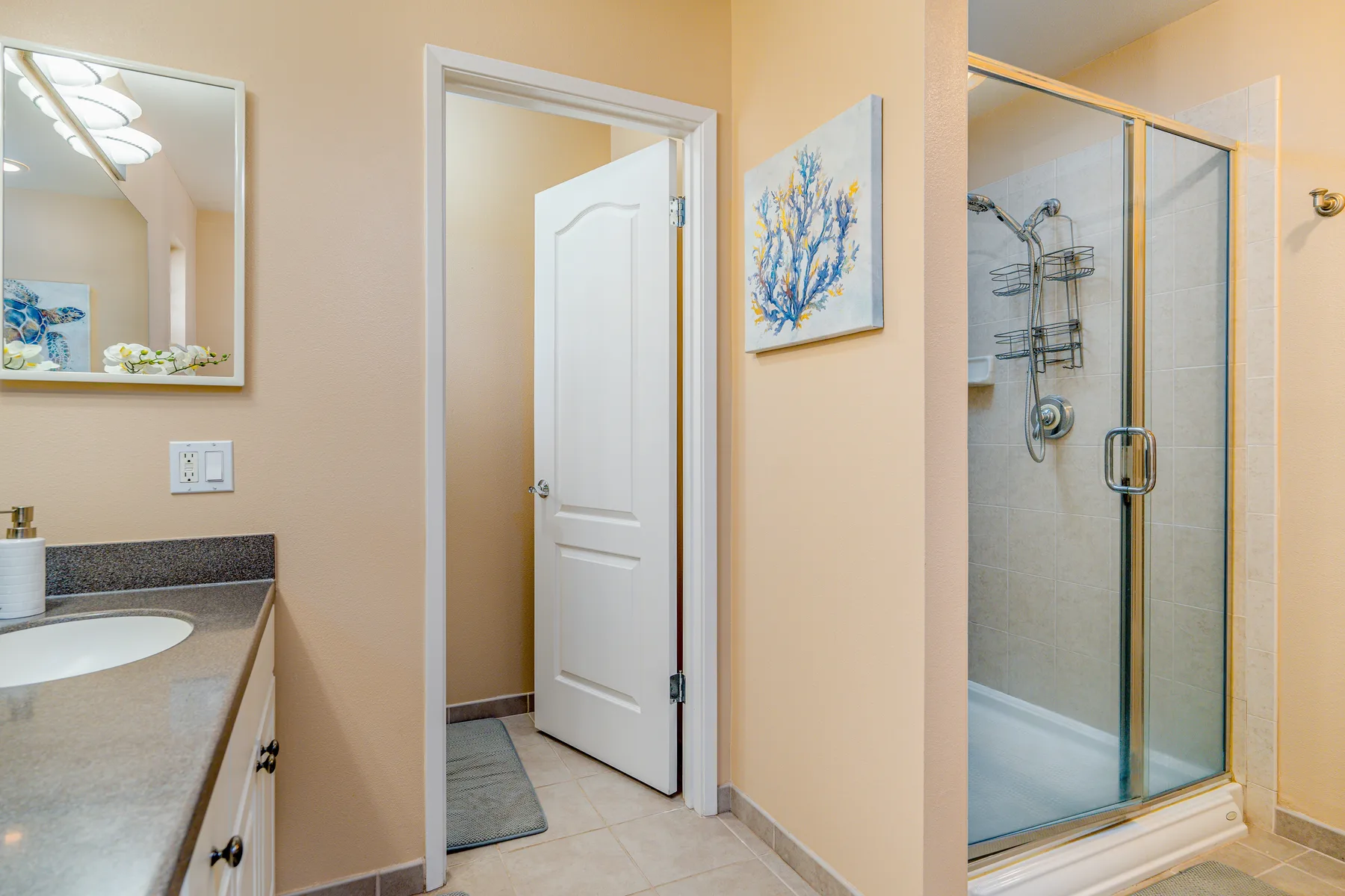 A bathroom with a vanity, a doorway, and a glass shower.