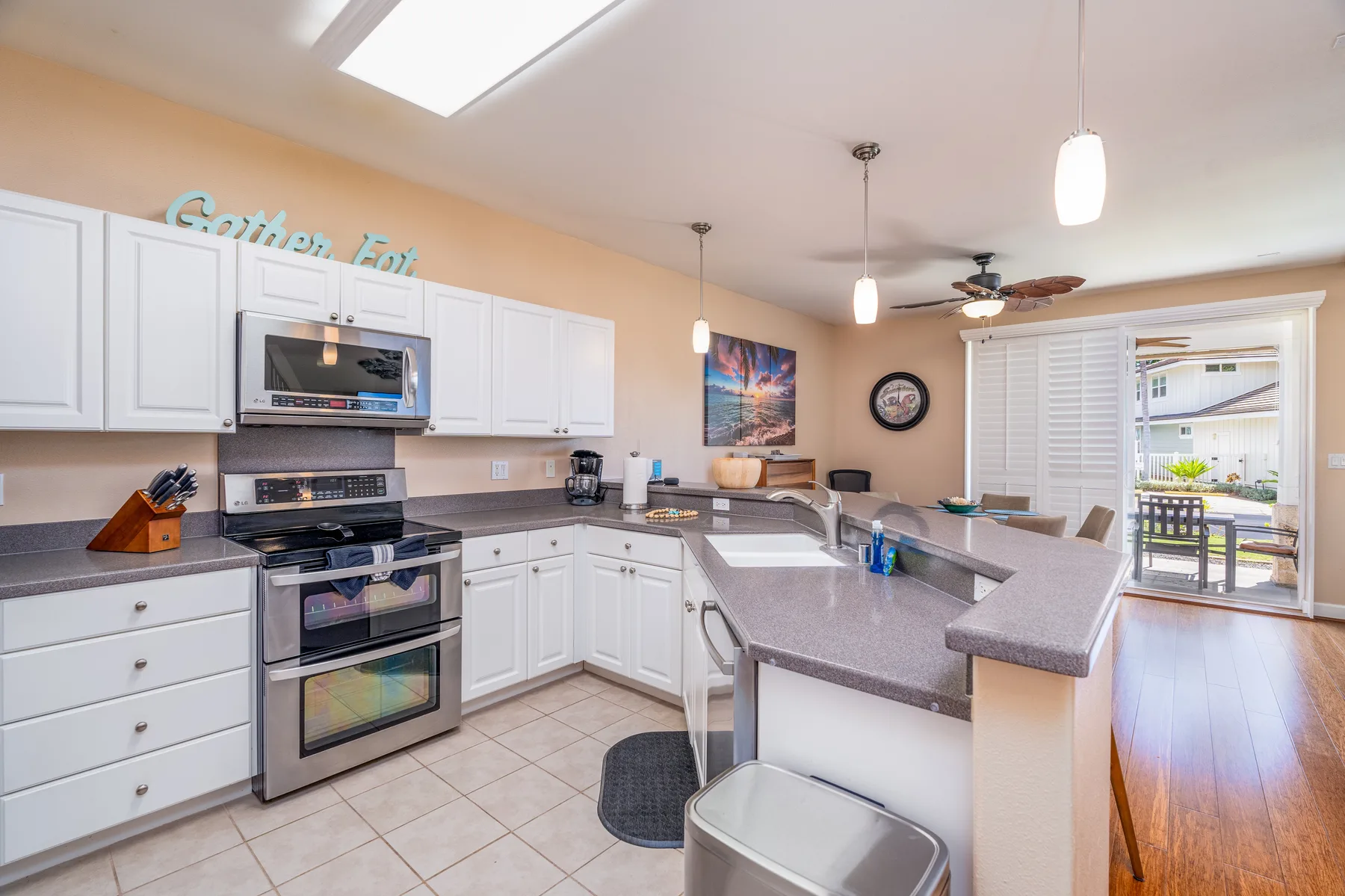 Una cocina luminosa con una isla larga y una puerta abierta al patio.