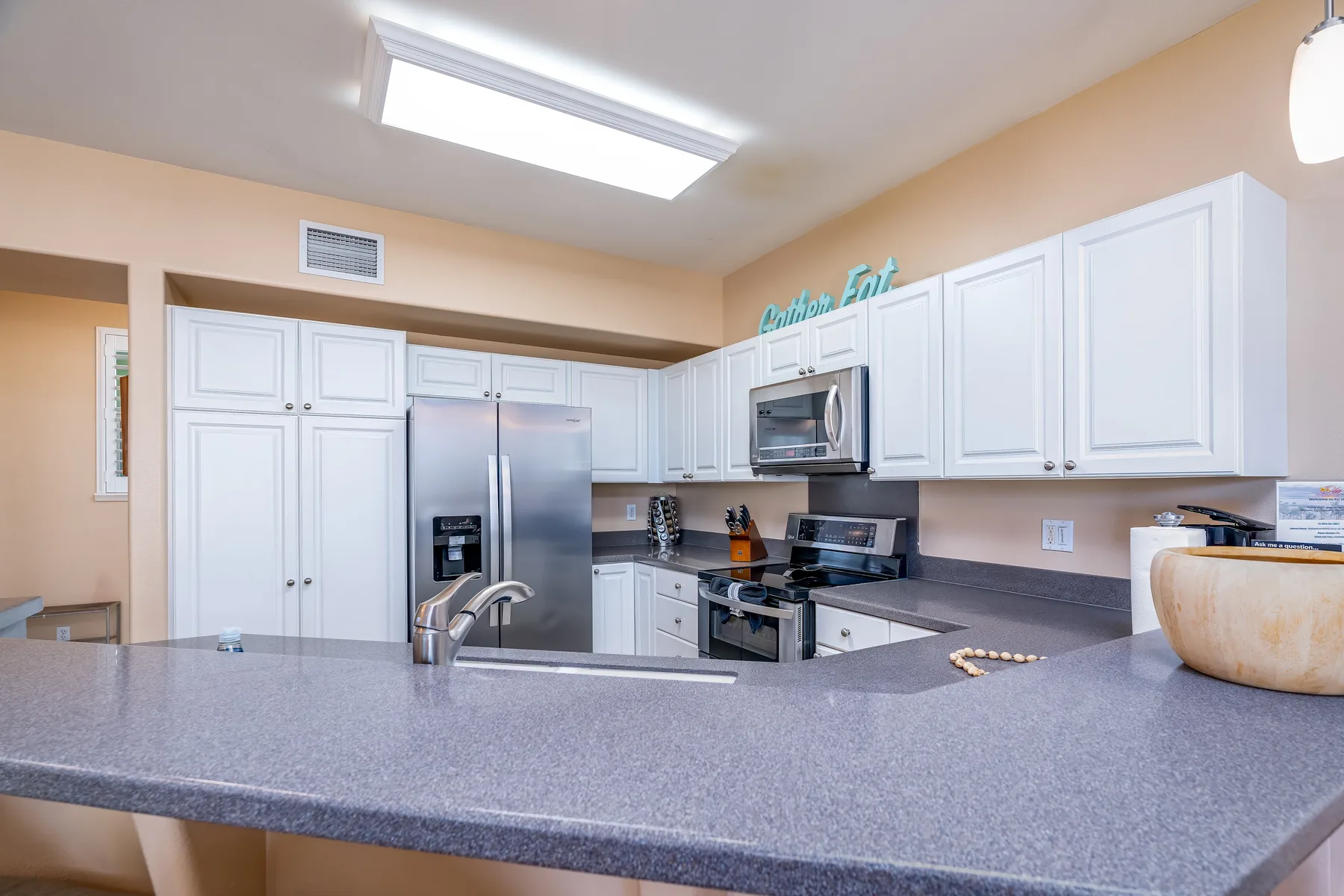 A kitchen with white cabinets, stainless steel appliances, and a wide counter.