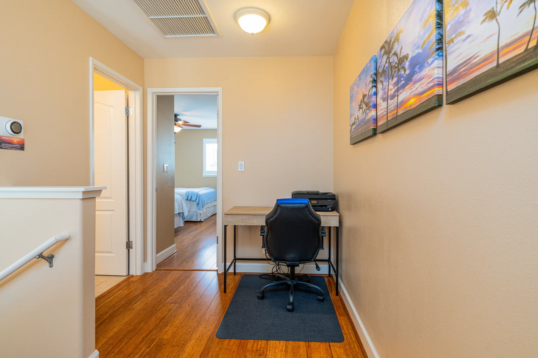 A small study area with a desk and chair sits beside a hallway.