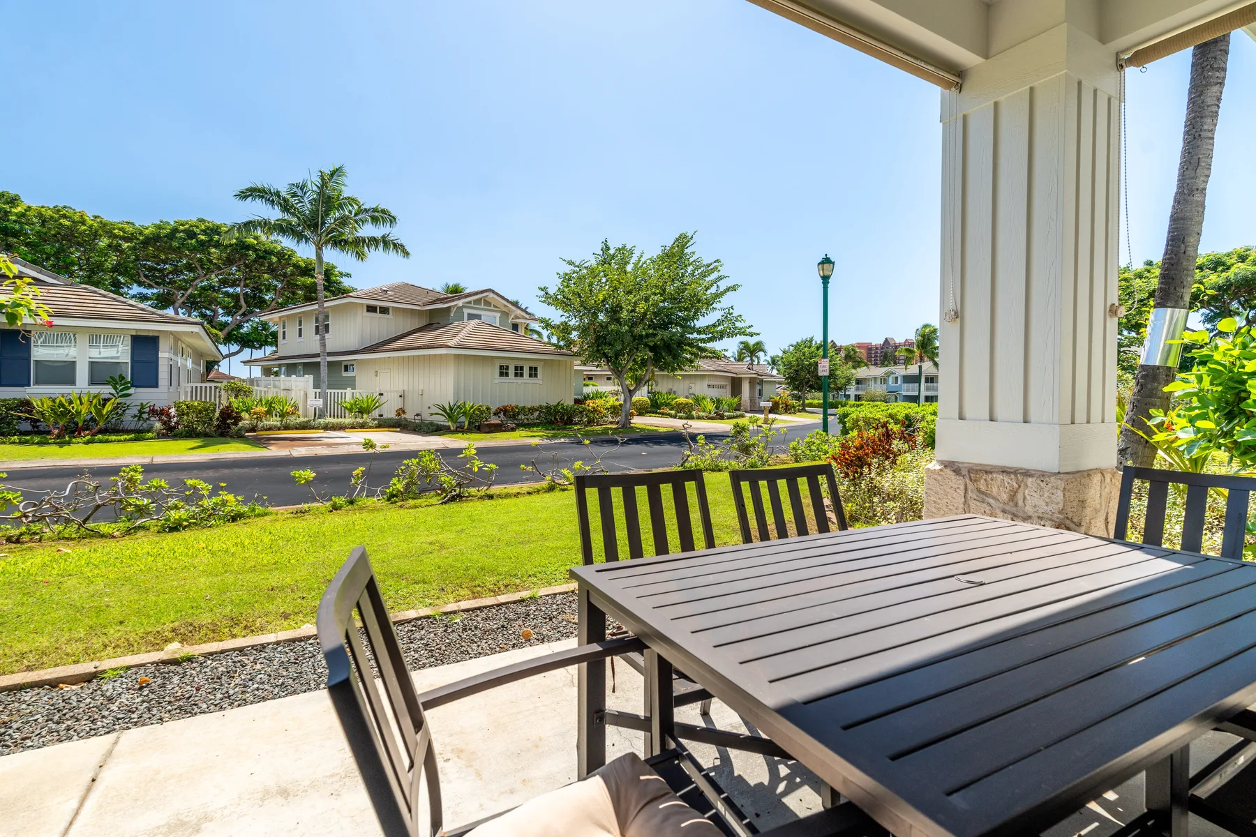 Un patio cubierto con una mesa de comedor da a una calle residencial y vegetación.