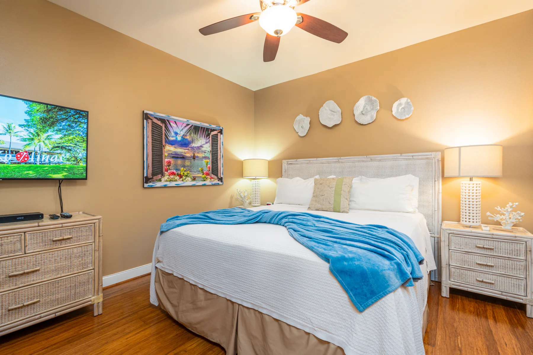 A bedroom with a neatly made bed and blue blanket.