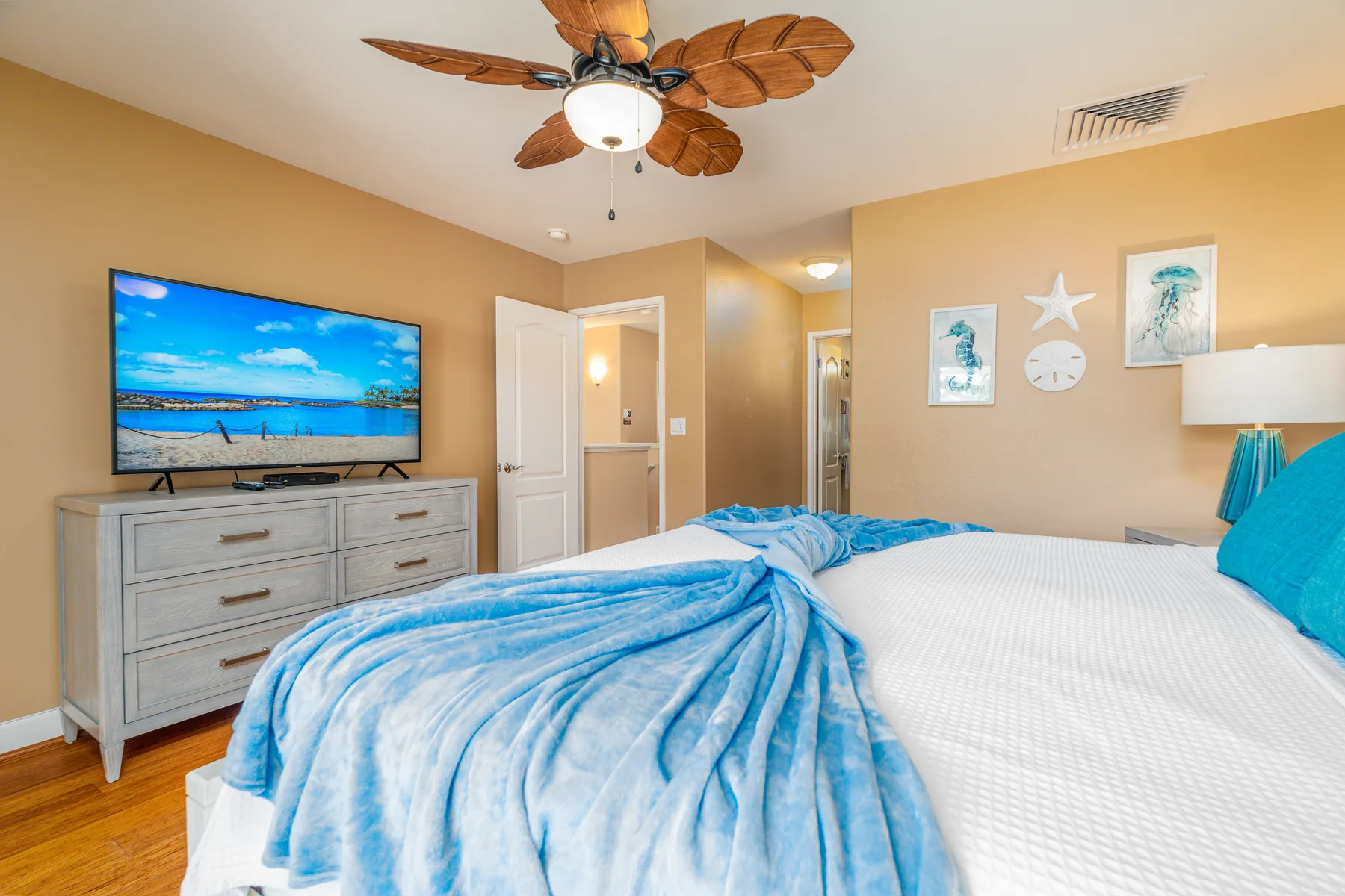 A bedroom with a bed, blue bedding, and a television on a dresser.