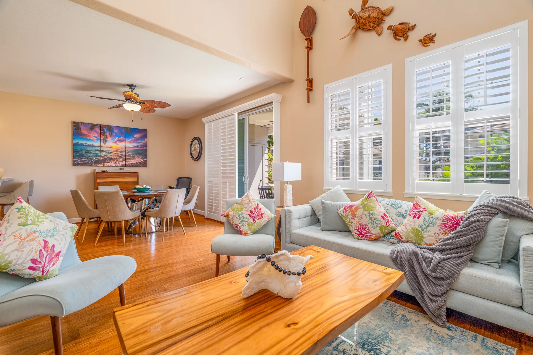 A bright living room with a seating area, wooden coffee table, and dining space.