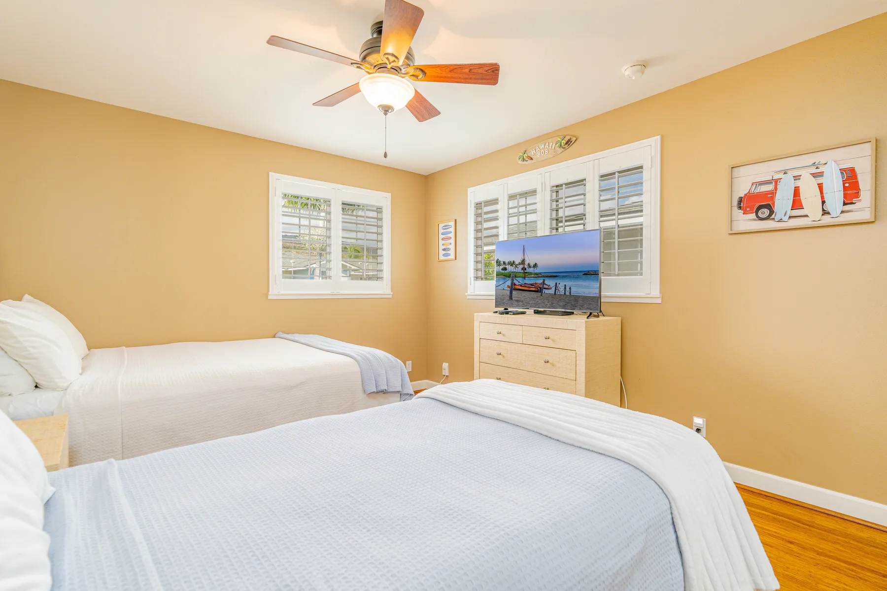 A bedroom with beds, a television, and windows.