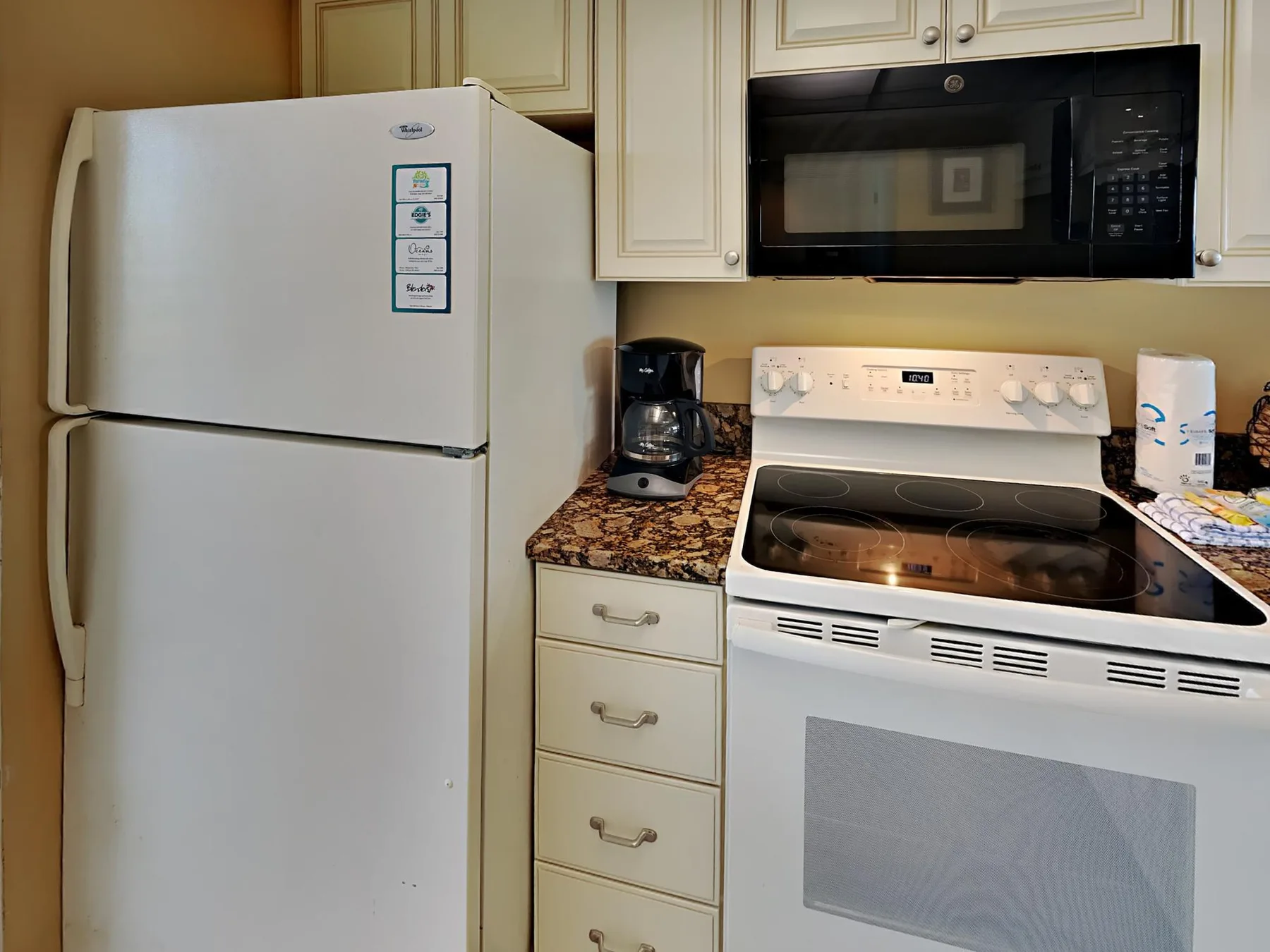Una cocina con refrigerador, estufa y microondas.