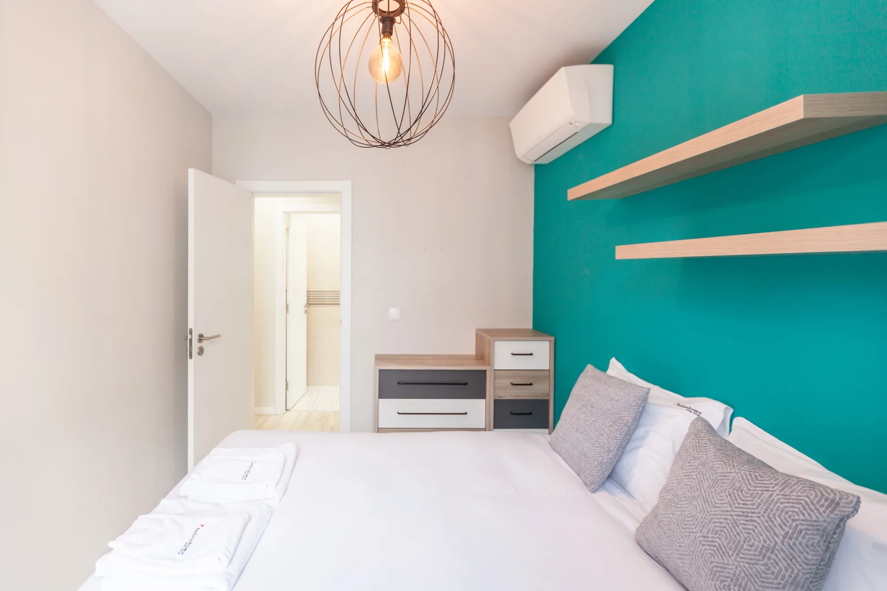 Bedroom with a bed and a teal accent wall.