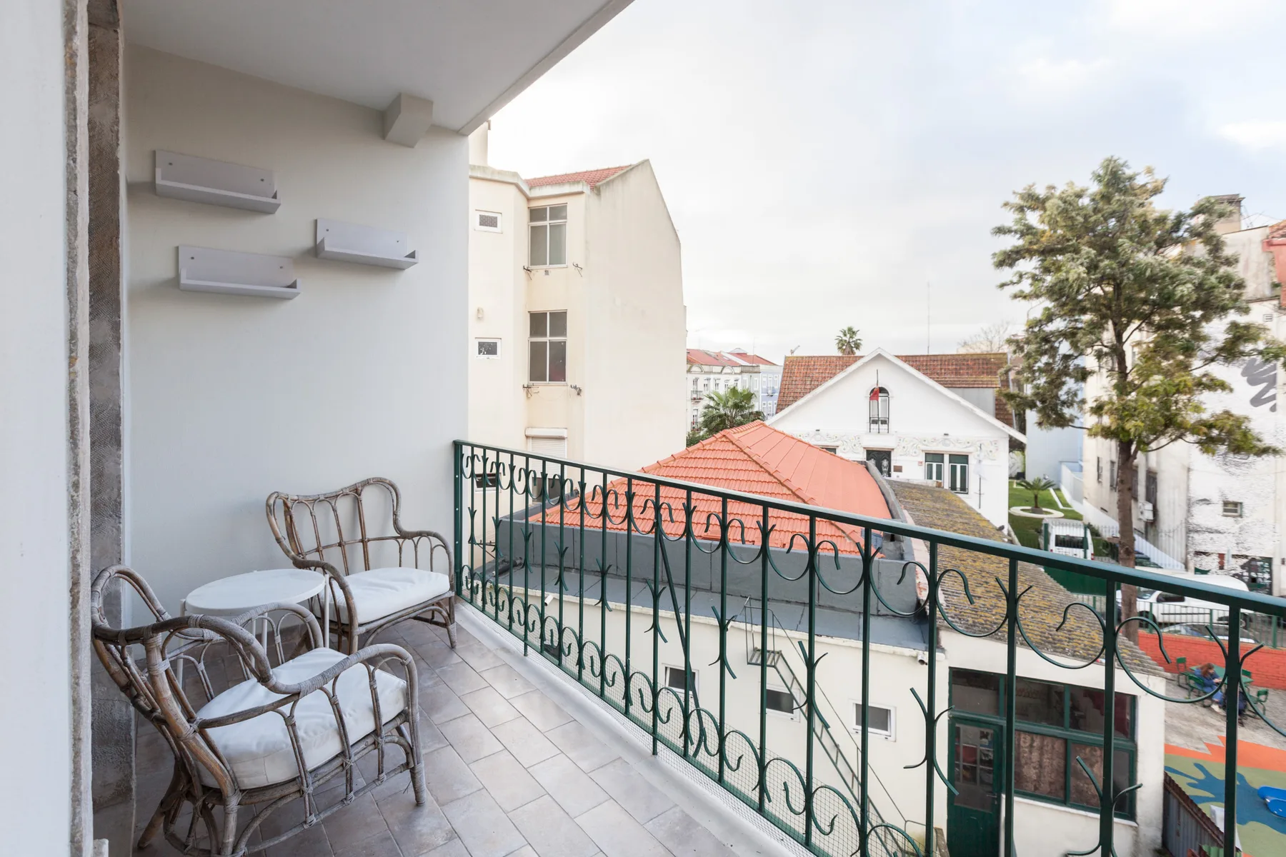 A balcony with seating overlooks nearby buildings and rooftops.
