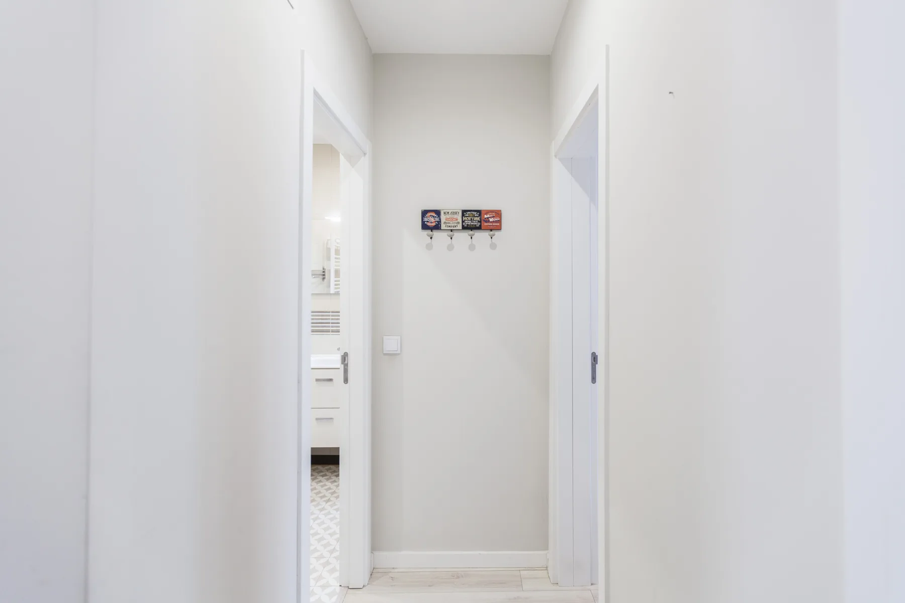 A bright hallway with white walls and doorways.