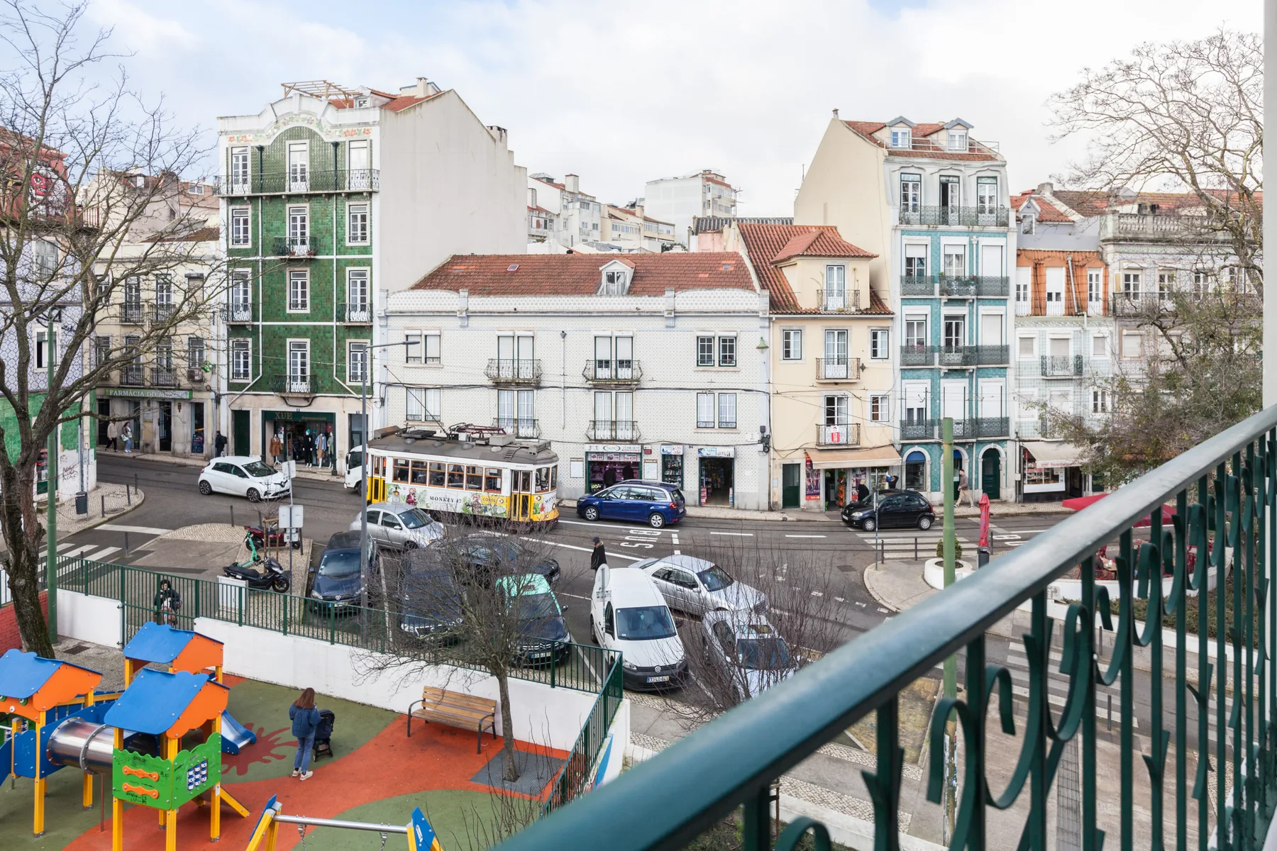 A city street and nearby playground are visible beyond a balcony railing.