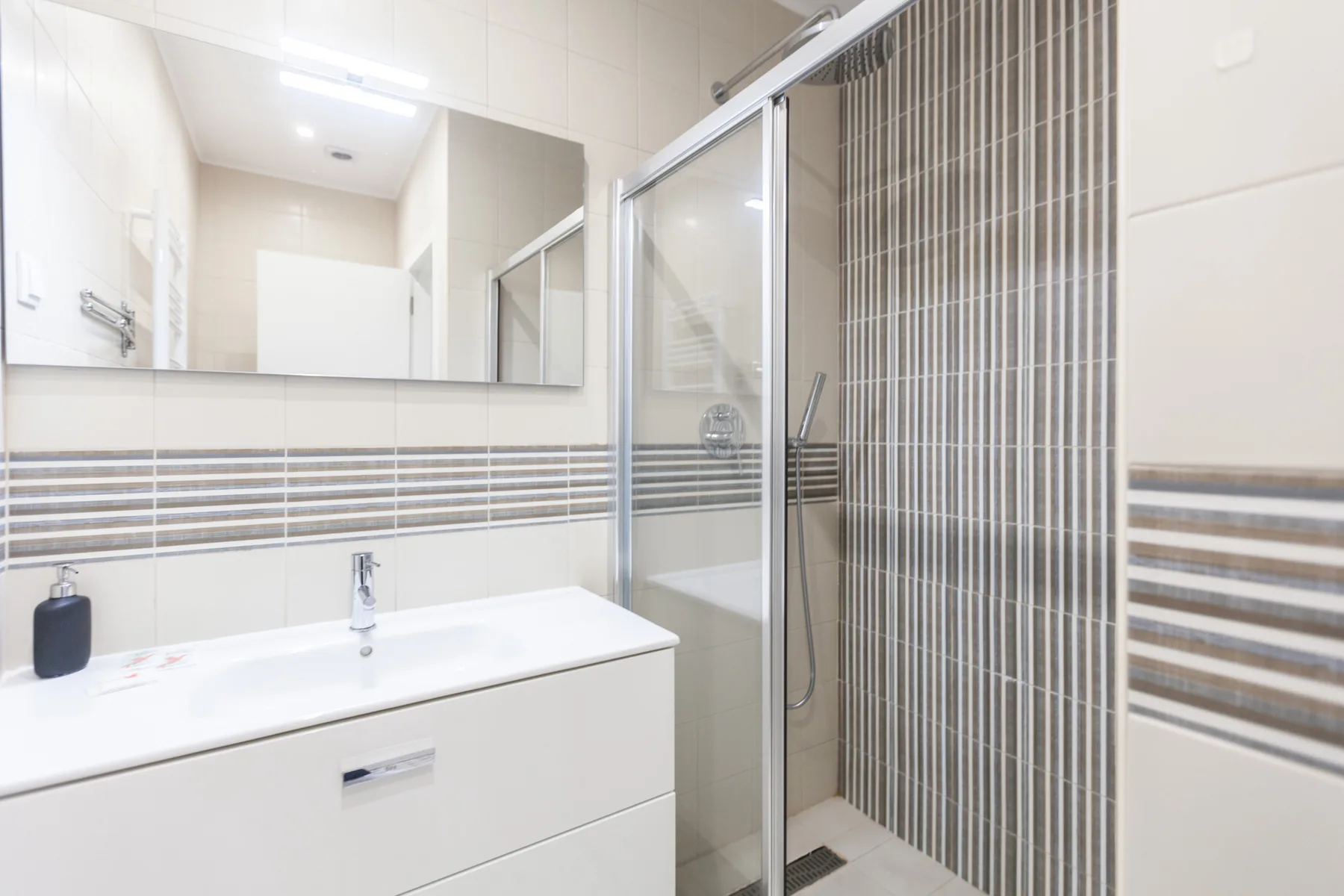 A bright bathroom with a white sink and a glass shower.