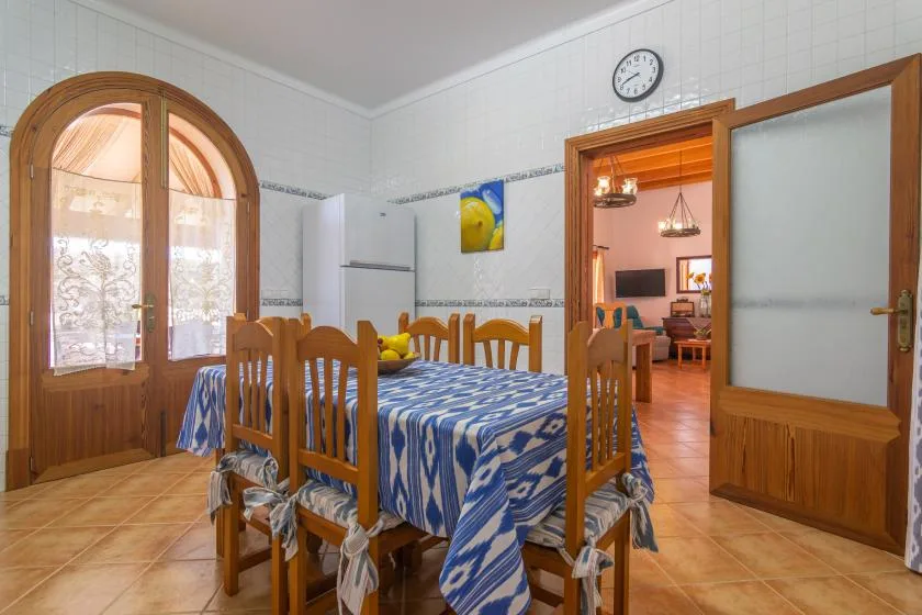 A dining room with a wooden table covered in a blue patterned cloth.