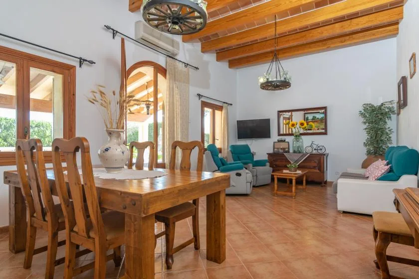 A living and dining room with a wooden table, seating, and exposed ceiling beams.