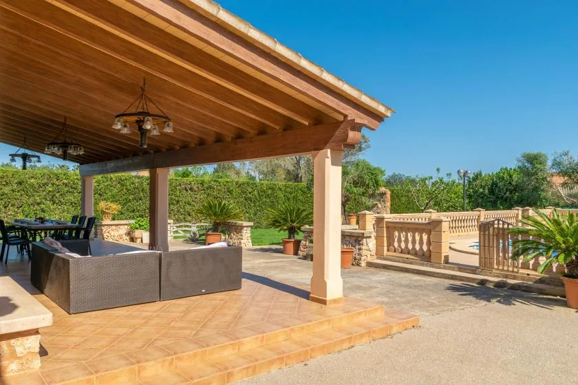 A covered outdoor seating area opens onto a sunny stone terrace.