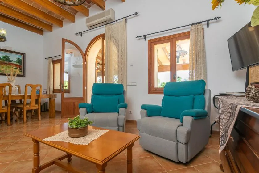 A living room with two teal armchairs and a wooden coffee table.