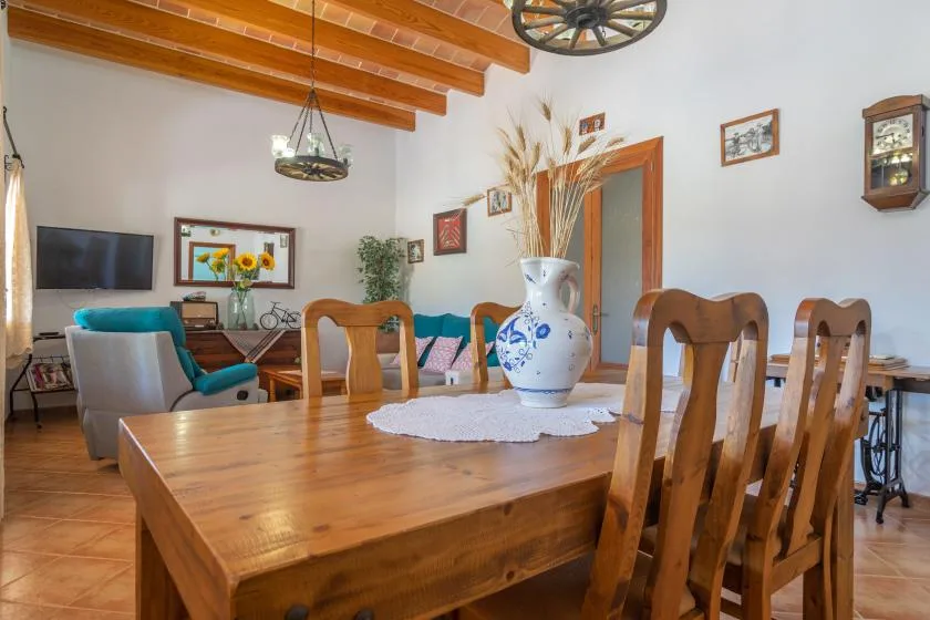 A dining area with a wooden table and chairs, with a sitting area in the background.