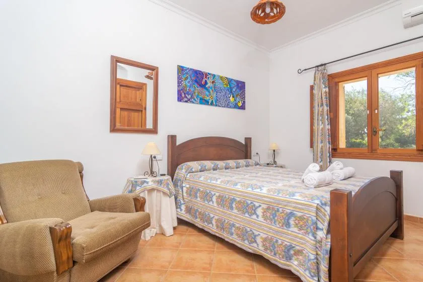 A bedroom with a wooden bed, patterned bedding, and a window overlooking trees.
