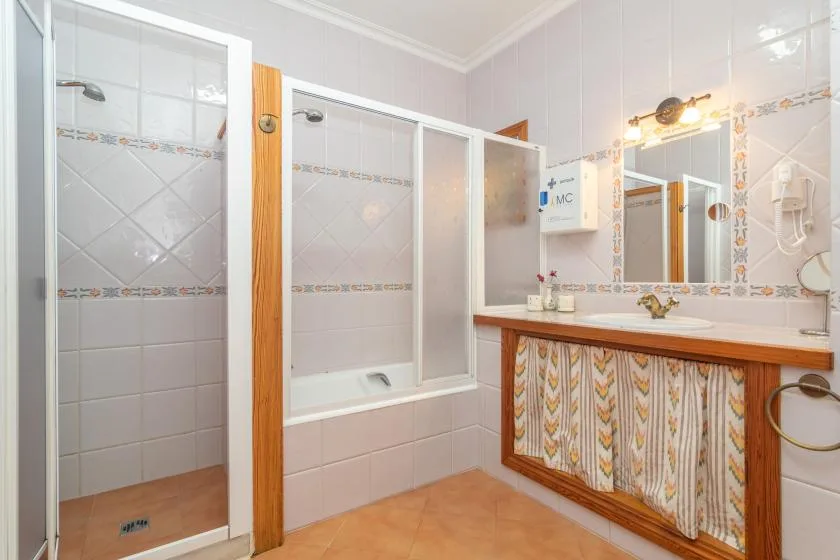 A tiled bathroom with a bathtub, shower, and sink.