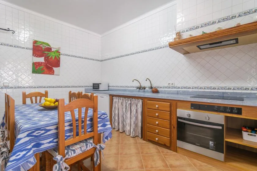 A tiled kitchen and dining area with a wooden table and built-in oven.