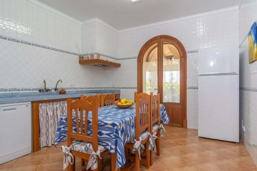 A tiled dining area with a wooden table and chairs beside an arched glass door.