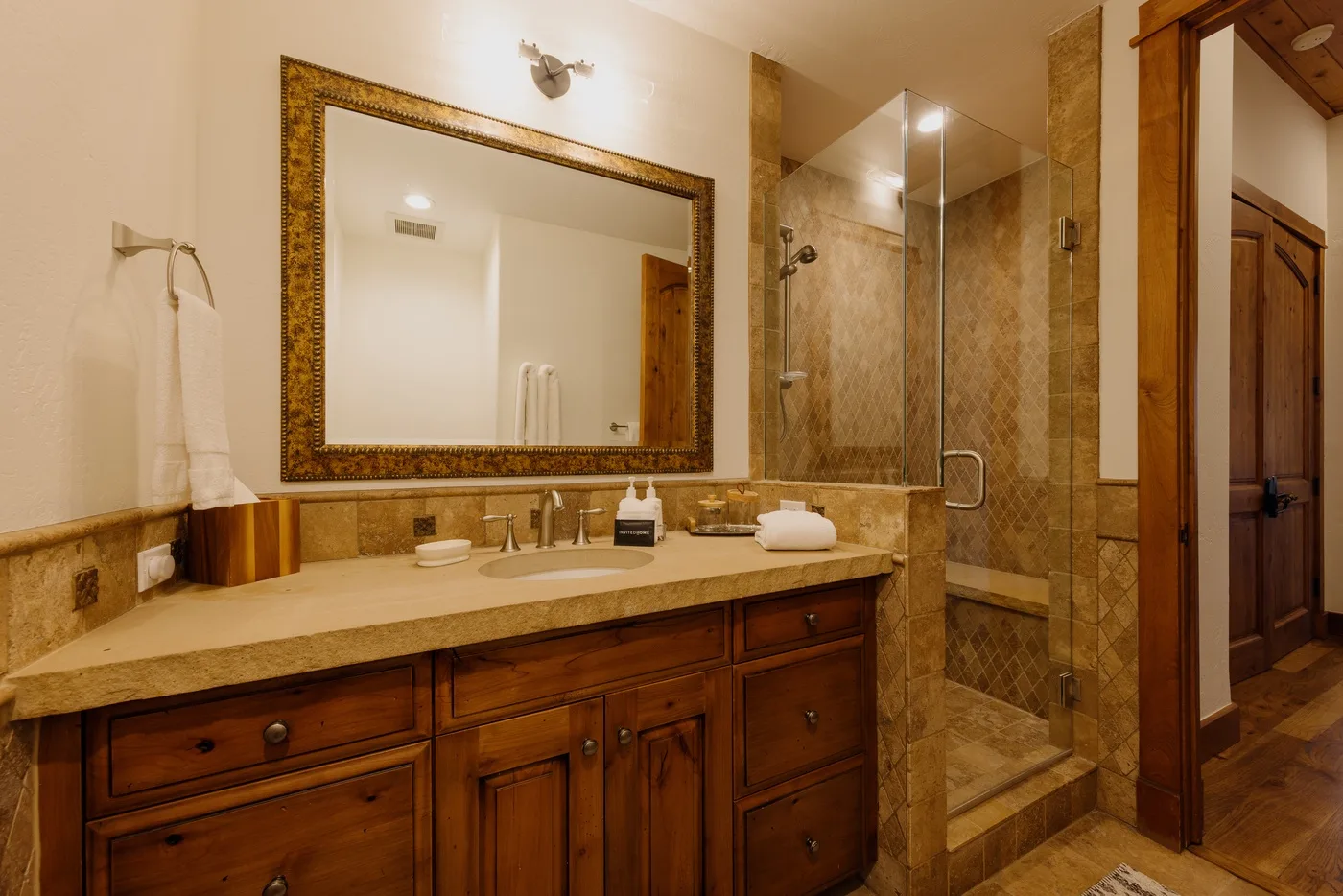 A bathroom vanity with a large mirror beside a glass shower.