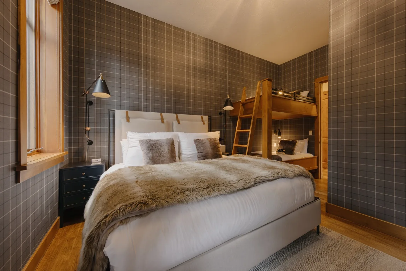A bedroom with a large bed and a wooden loft bed beside it.