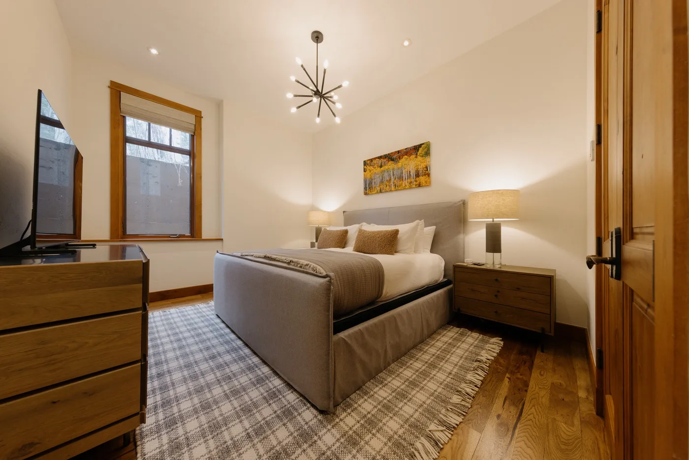 A bedroom with a bed, bedside tables, and windows.