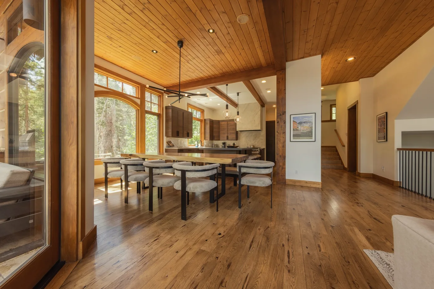 A spacious dining area with a long table, seating, and large windows.