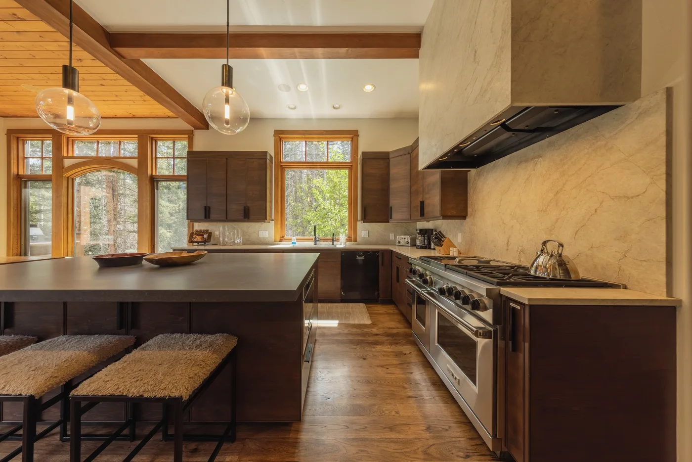 A spacious kitchen with a central island, wood cabinetry, and large windows.