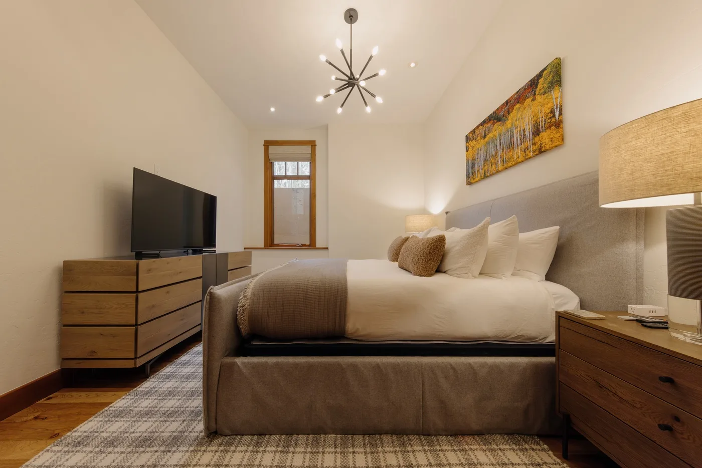 A bedroom with a bed, television, and bedside tables.