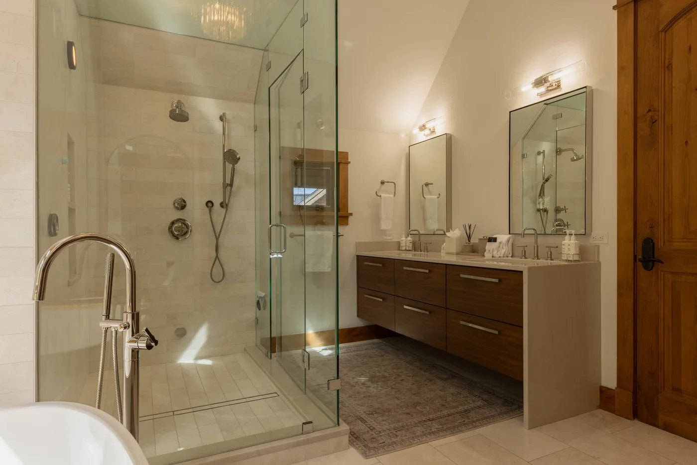 A modern bathroom with a glass shower and a long vanity with mirrors.